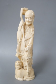 A Japanese carved walrus ivory figure of Fukurokuju, early 20th century,standing on the back of a tiger holding his staff, inset red seal mark to base, height 22cm